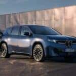 A blue 2027 BMW iX3 is charging at a BMW dealer near Martinsville.