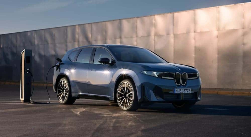 A blue 2027 BMW iX3 is charging at a BMW dealer near Martinsville.