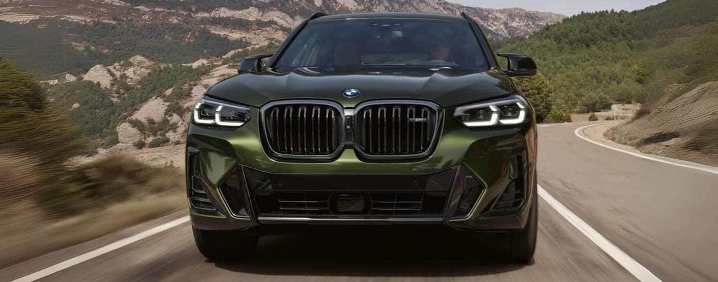 Green 2024 BMW X3 M50 driving down the road