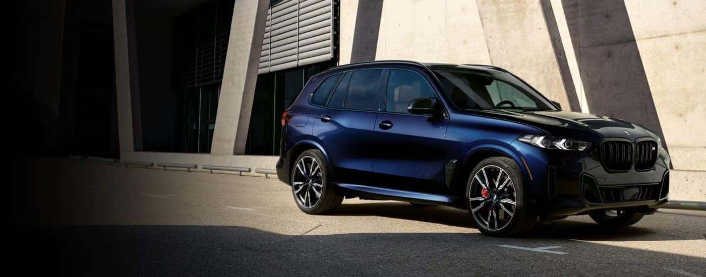Blue 2024 BMW X5 parked by a building