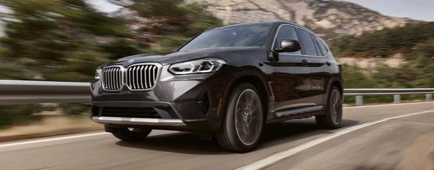 A black 2024 BMW X3 driving down a highway