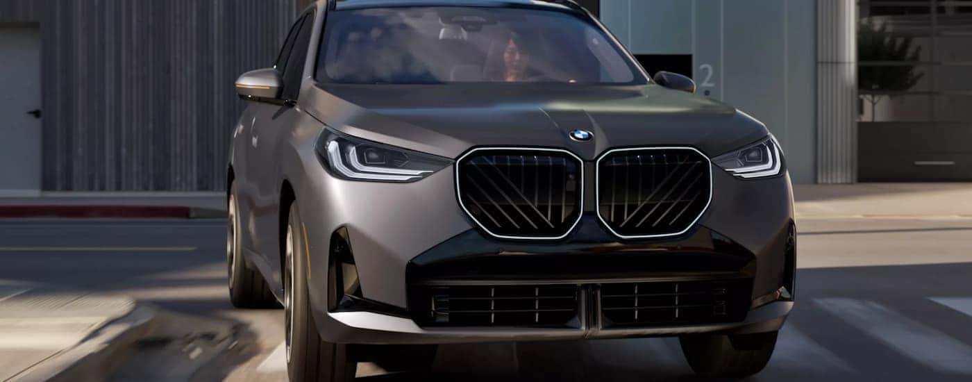 A gray 2026 BMW X3 driving on a city street for sale near Cave Spring