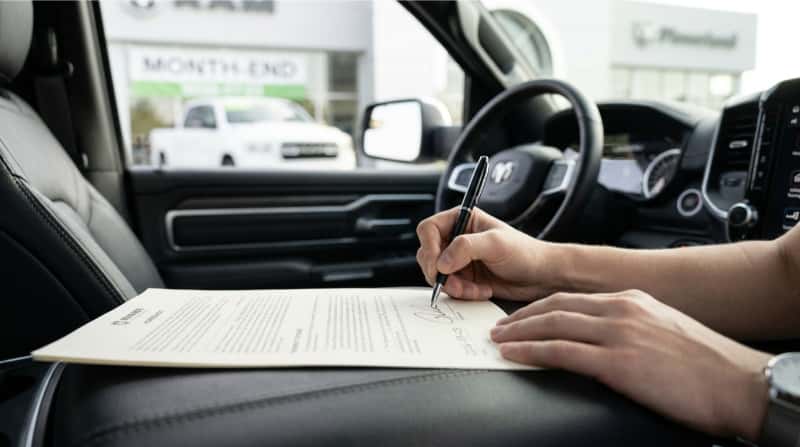Customer signing paperwork to secure a Dodge or RAM dealership offer before incentives expire.
