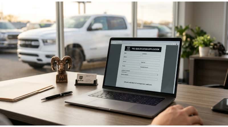 Online pre-qualification application for used RAM truck financing on a laptop at a dealership.