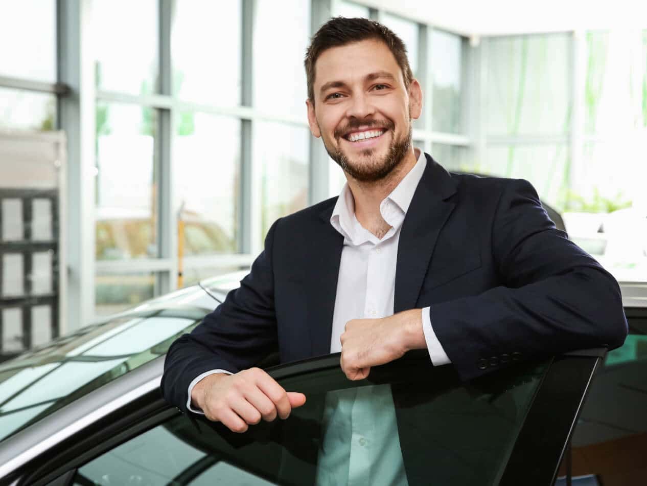 Man smiling while resting his arms on car door