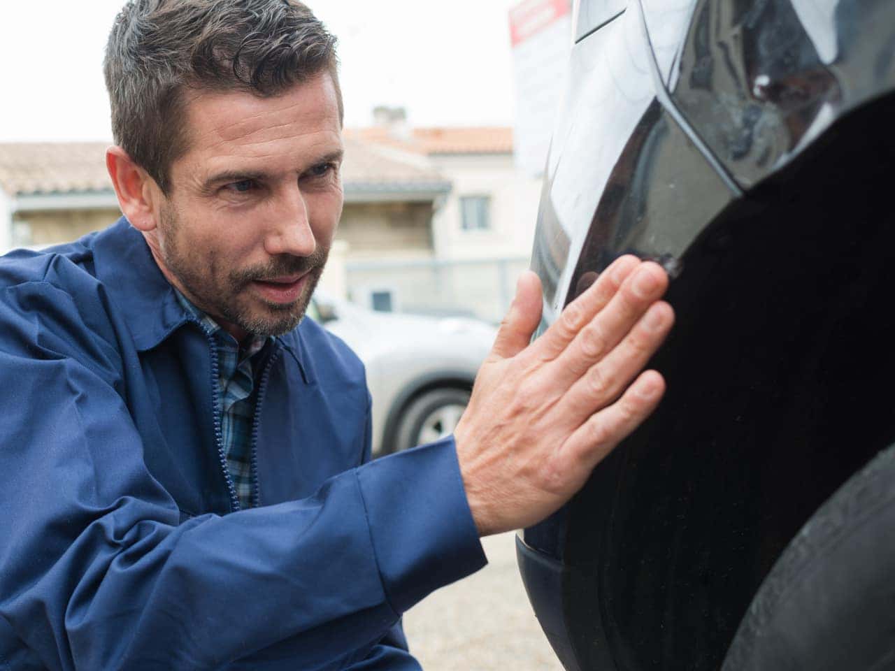 A mechanic inspects a car. The scene conveys focus and technical expertise.