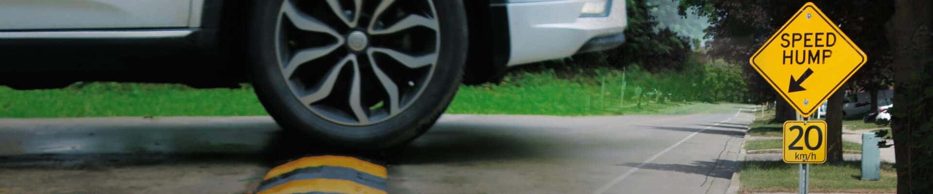 A side view of a car going over a speed bump with a speed bump sign superimposed over.